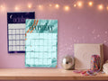 2027 Lyrical wall calendar, October and December on a fan bedroom wall with fairy lights and friendship bracelets